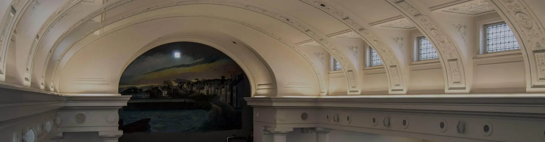 An ornate arched ceiling with a mural in a historic building interior.