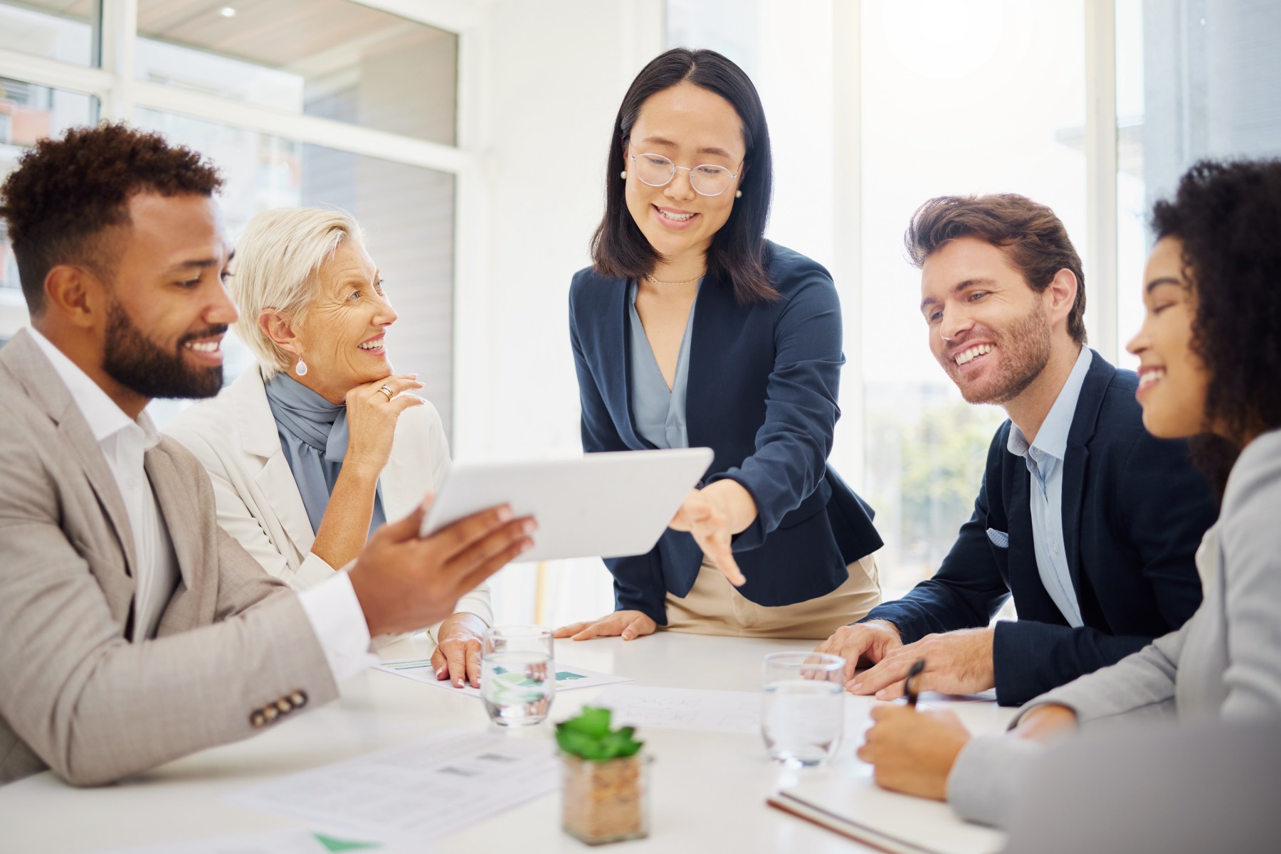Diverse business team collaborating in office meeting with tablet