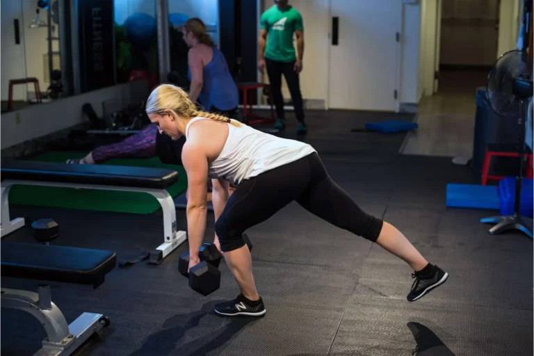 A woman performing a kettlebell exercise in a gym.