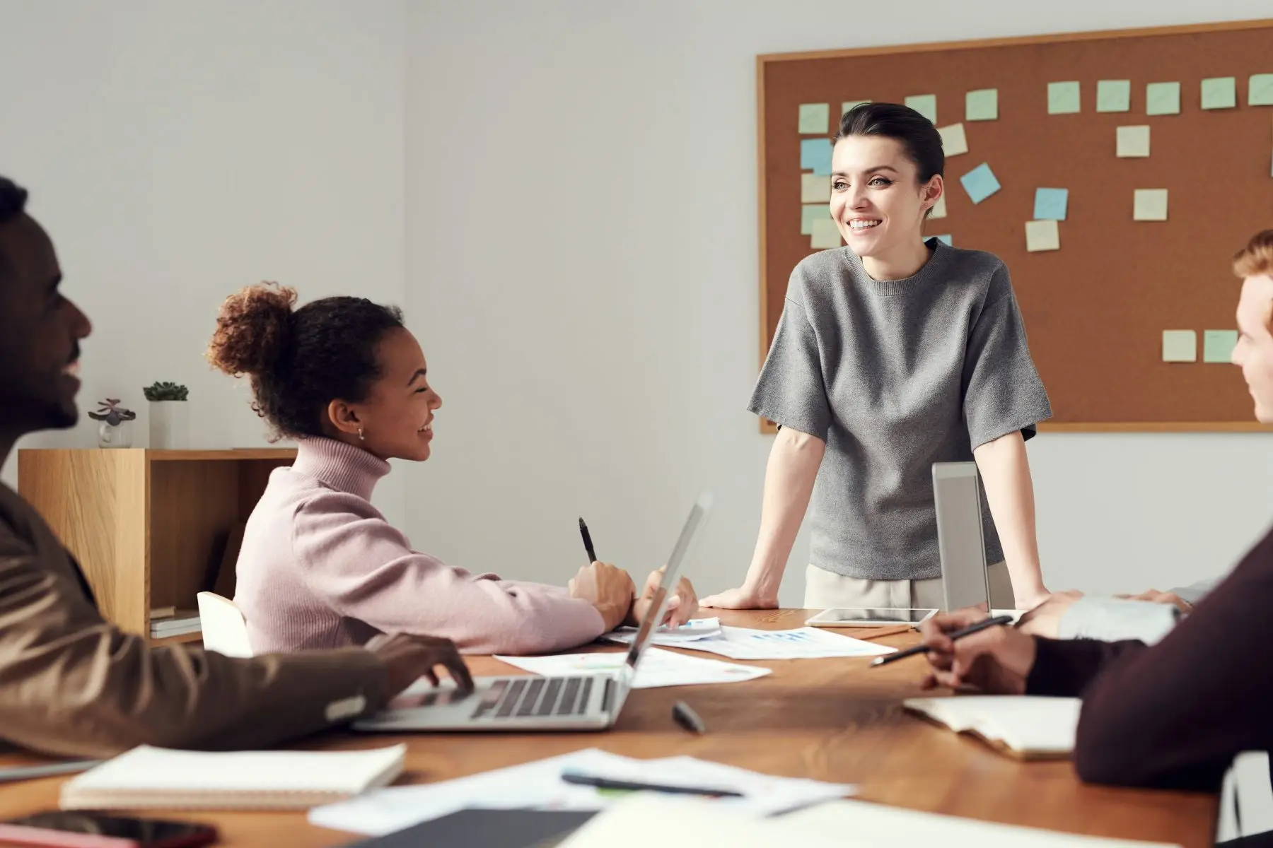 A woman leading a meeting with colleagues around a table.