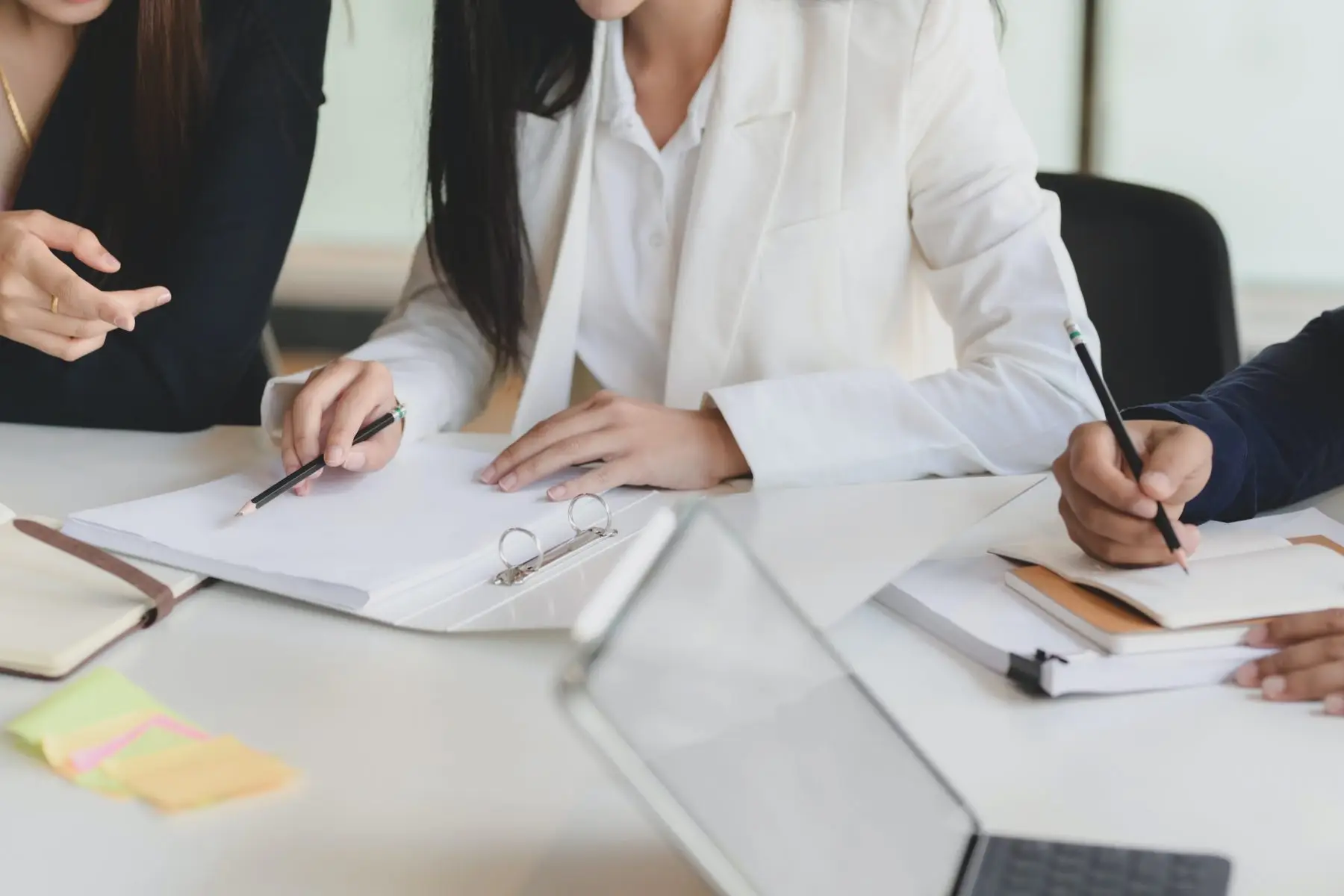 Close-up of colleagues reviewing and signing documents at a table.