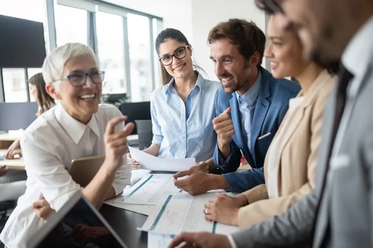 A group of colleagues laughing during a lively meeting around a table.