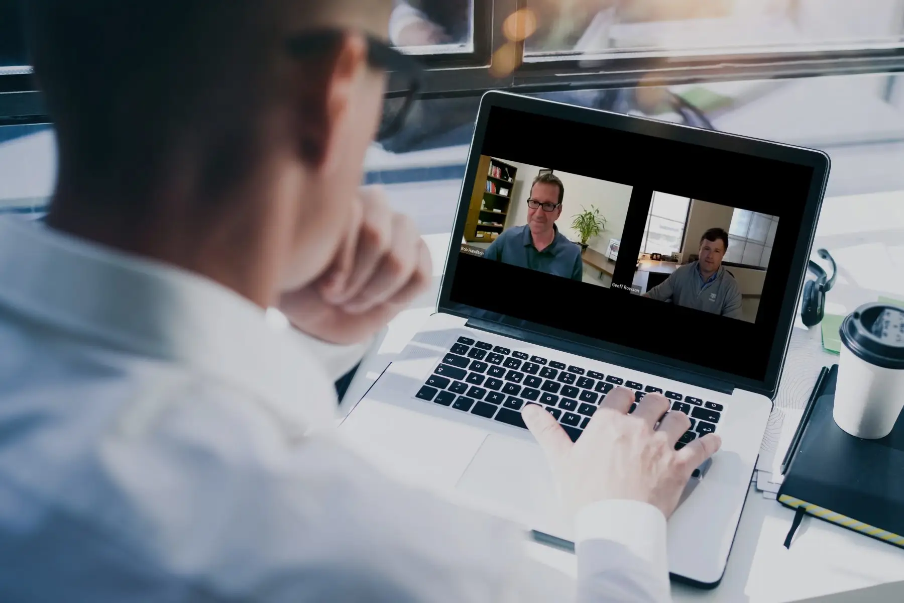 A man on a video conference call with colleagues on his laptop.