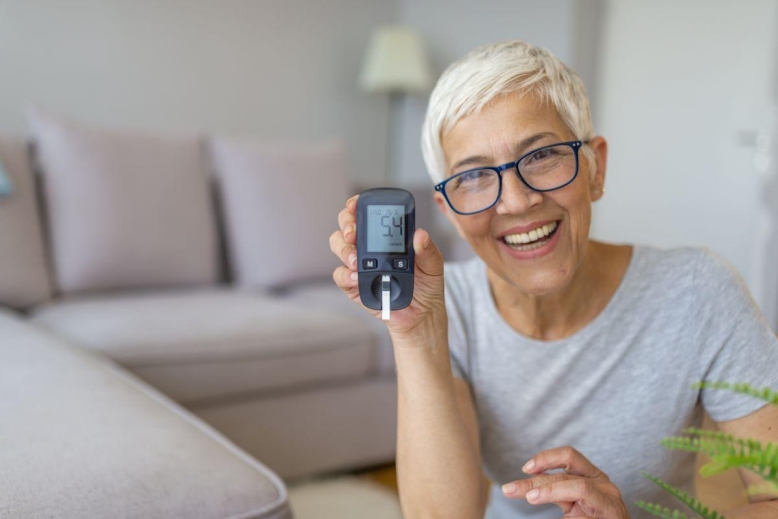 smiling woman using a glucometer