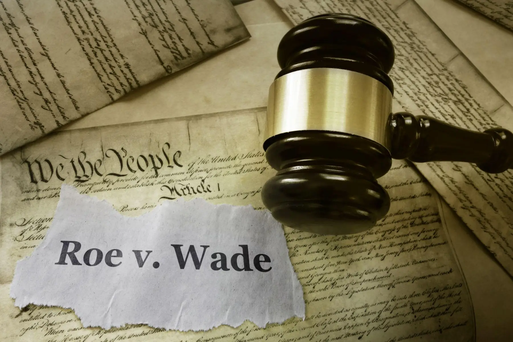 A gavel on a copy of the U.S. Constitution beside a torn paper reading Roe v. Wade.
