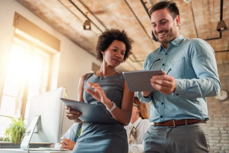 A man and woman looking at a tablet together in an office.