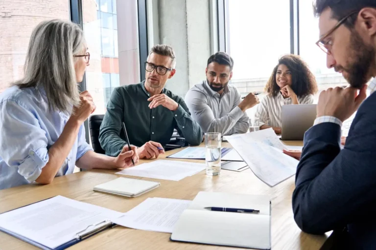 A diverse group in a discussion around a conference table with documents.
