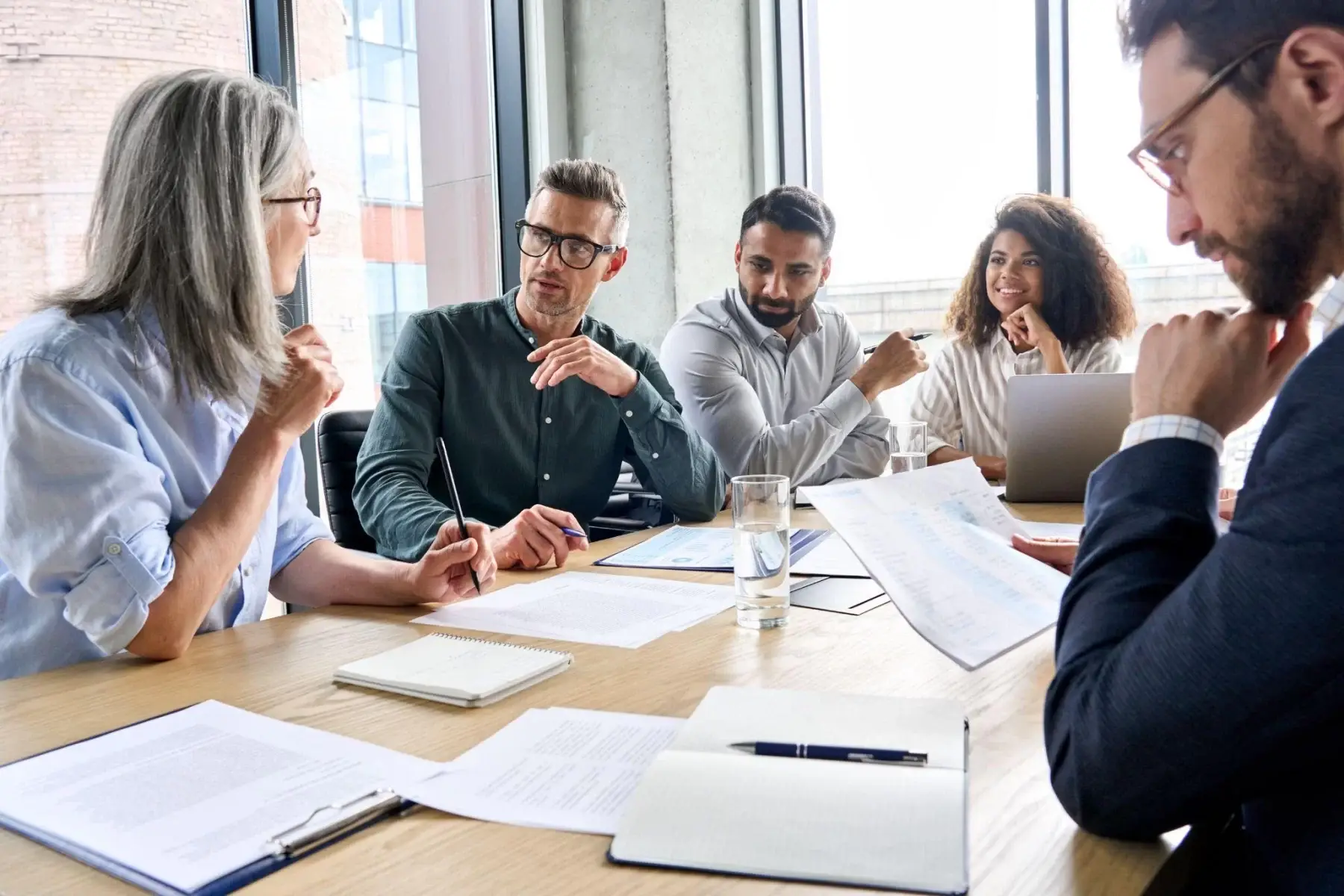 A diverse group in a discussion around a conference table with documents.