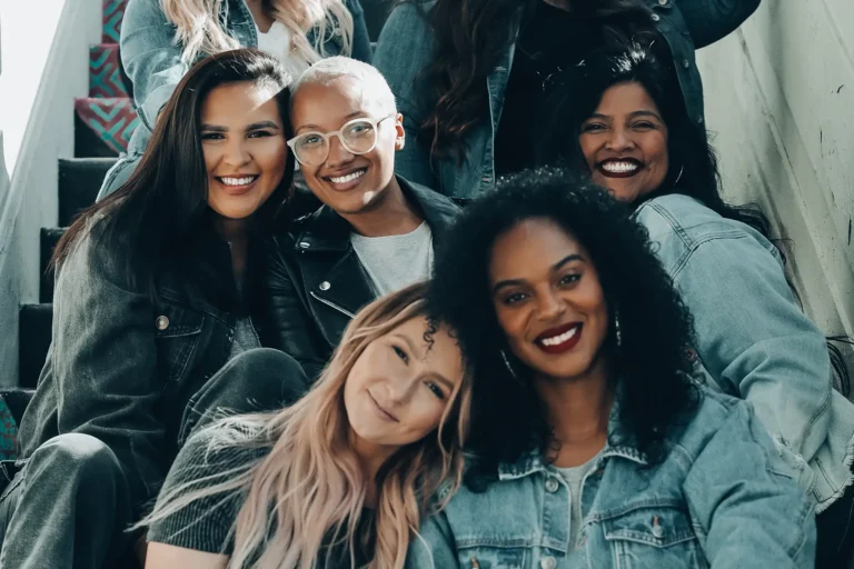 A group of smiling young friends posing together on a staircase.