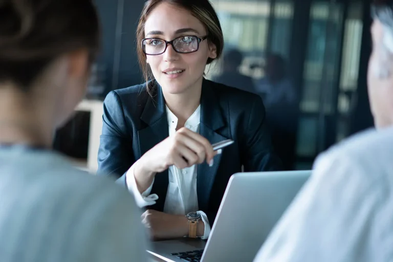 A businesswoman talking with colleagues across a table during a meeting.