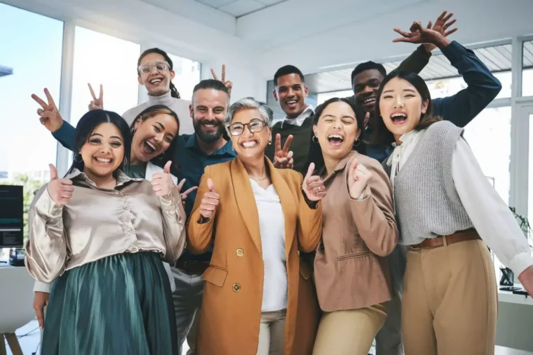 A diverse group of colleagues cheering and celebrating together in an office.