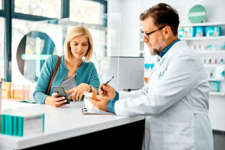 A pharmacist helping a smiling customer at a pharmacy counter.