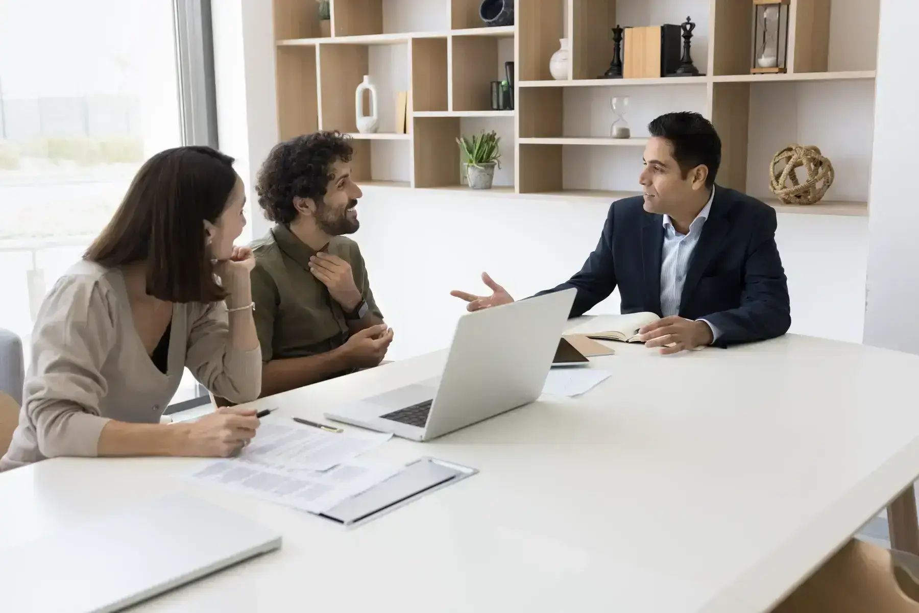 A couple meeting with an advisor at a desk with a laptop and documents.