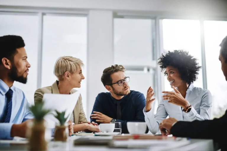 A diverse group of professionals in an animated discussion around a table.