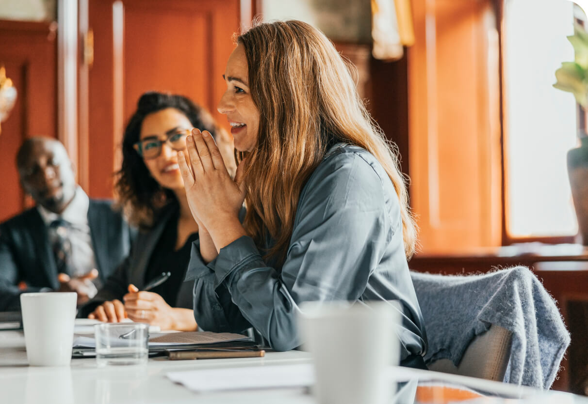A smiling woman in conversation with colleagues in a business meeting