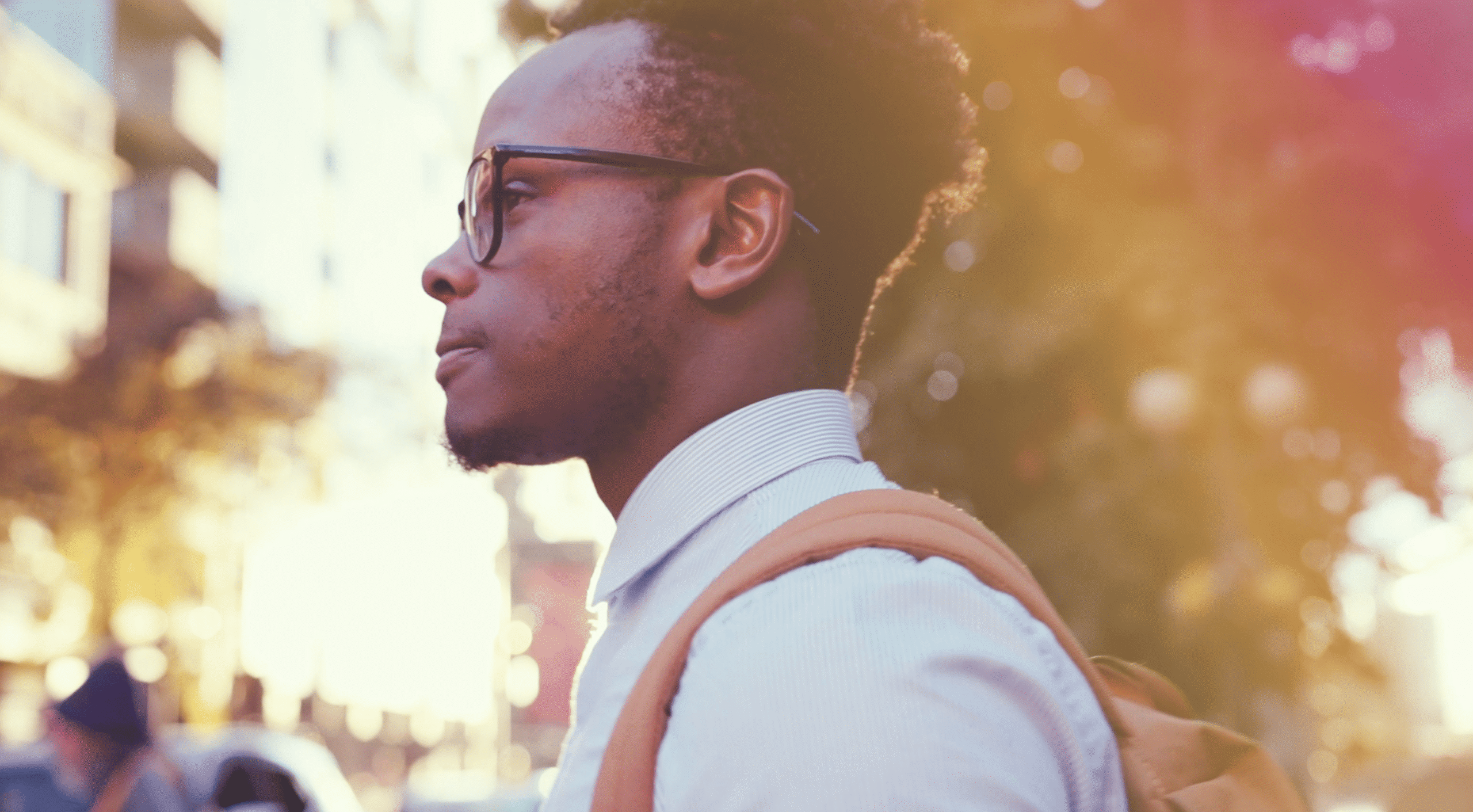 A young professional with a backpack walking along a sunny city street