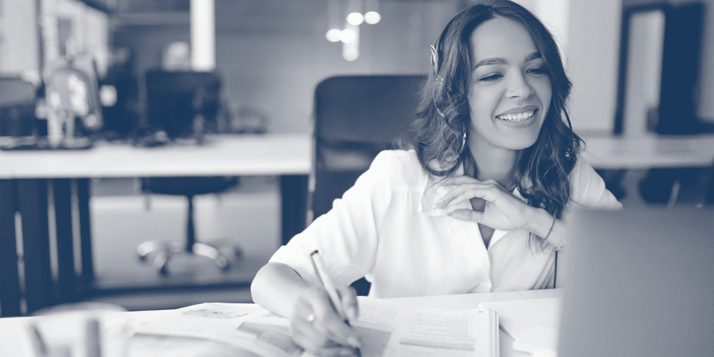A smiling professional working at a laptop and taking notes