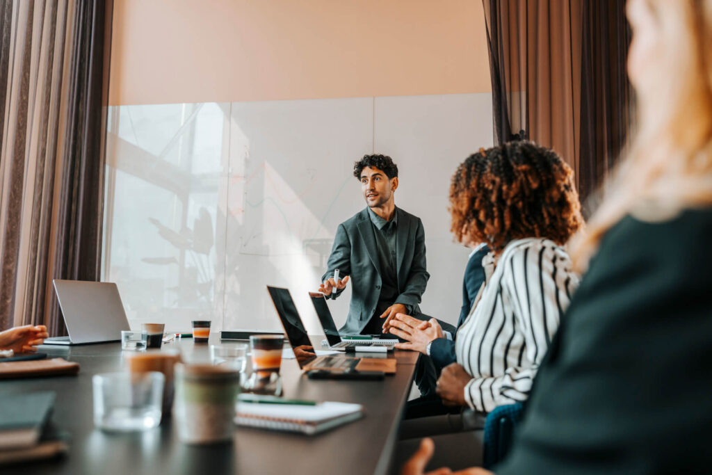 An advisor presenting to a small group of seated colleagues in a meeting room