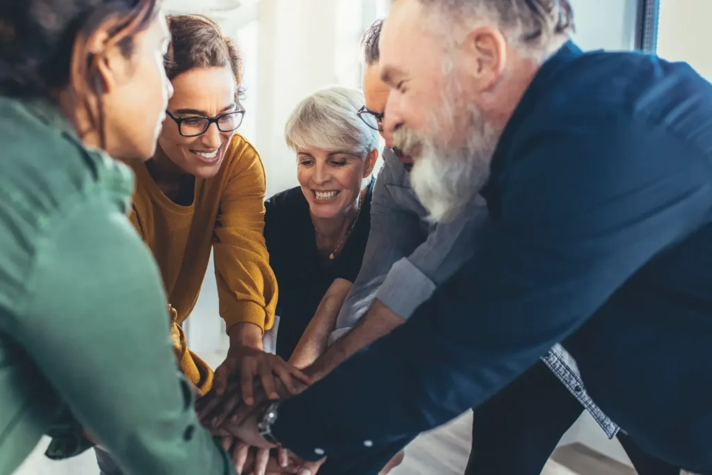 Smiling colleagues joining hands together in an office meeting