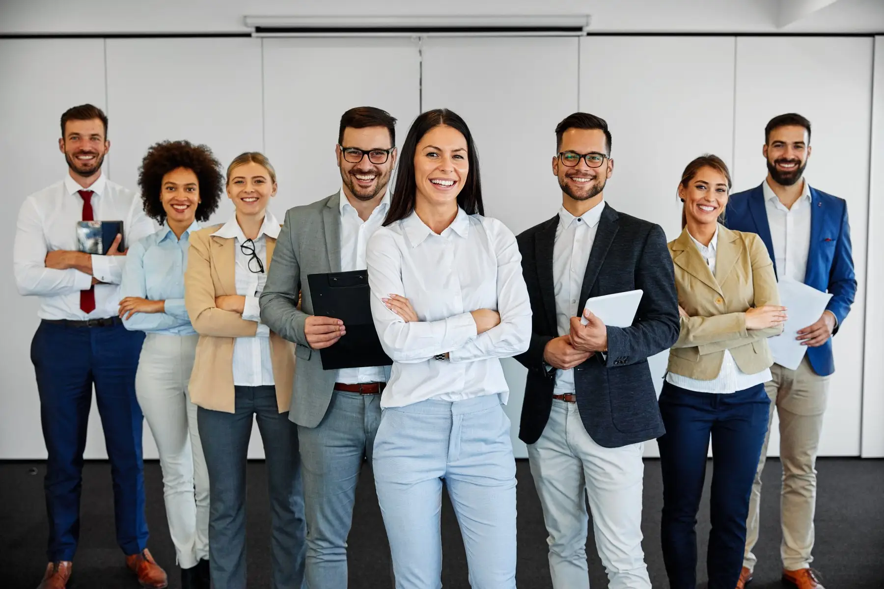 A diverse group of business professionals standing in a row, smiling.