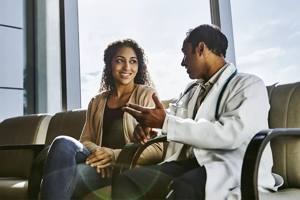 A woman smiling and conversing with her healthcare provider